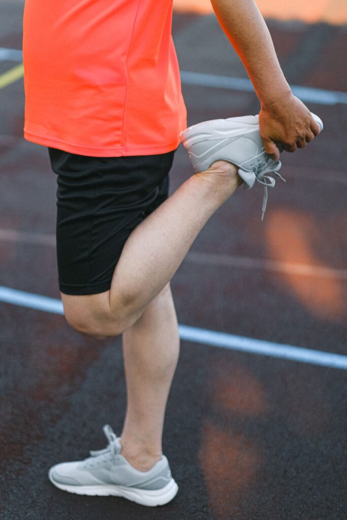 An athlete in sportswear stretching legs on a running track before training