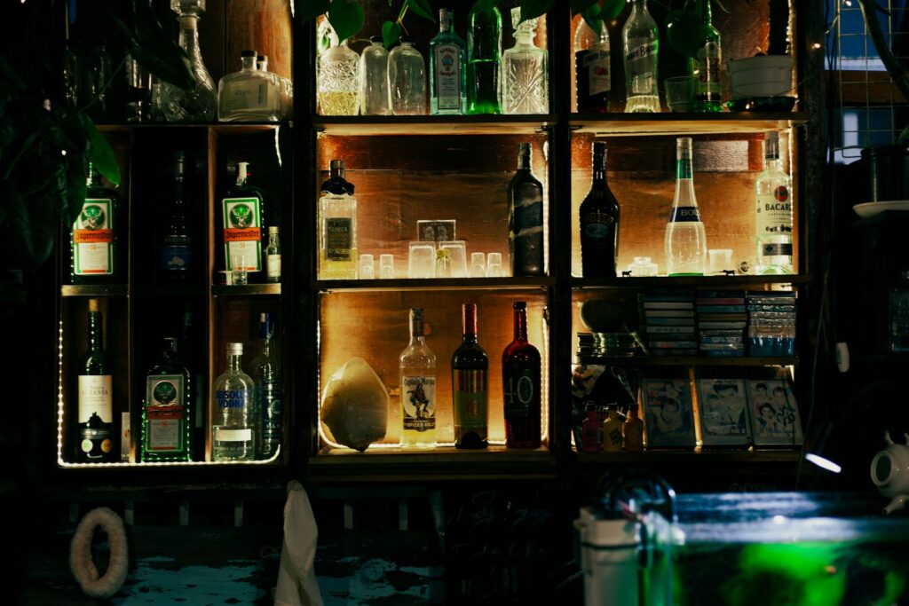 A glowing bar shelf displaying various liquor bottles