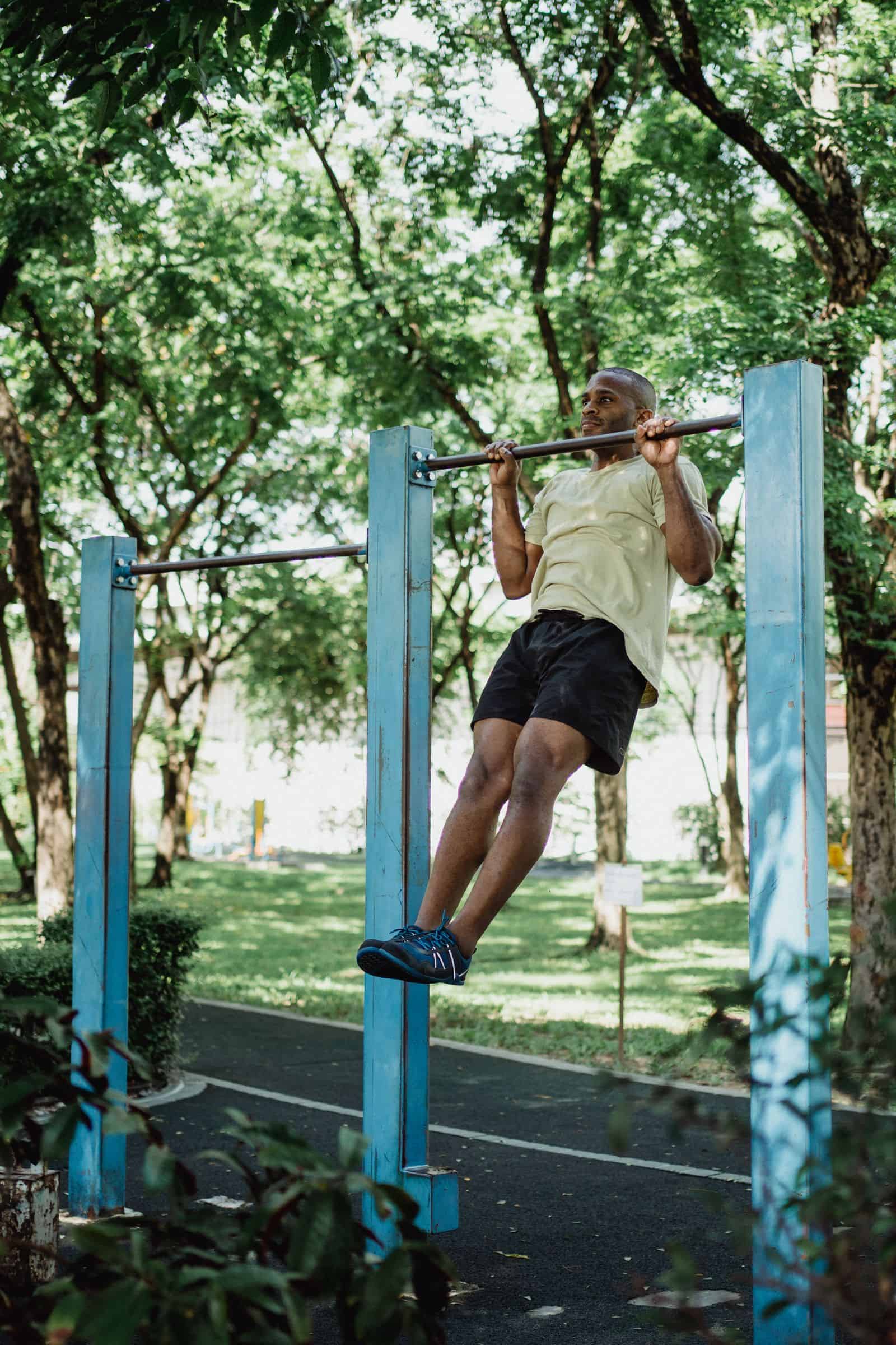 A man performing pull-ups outdoors in a park setting