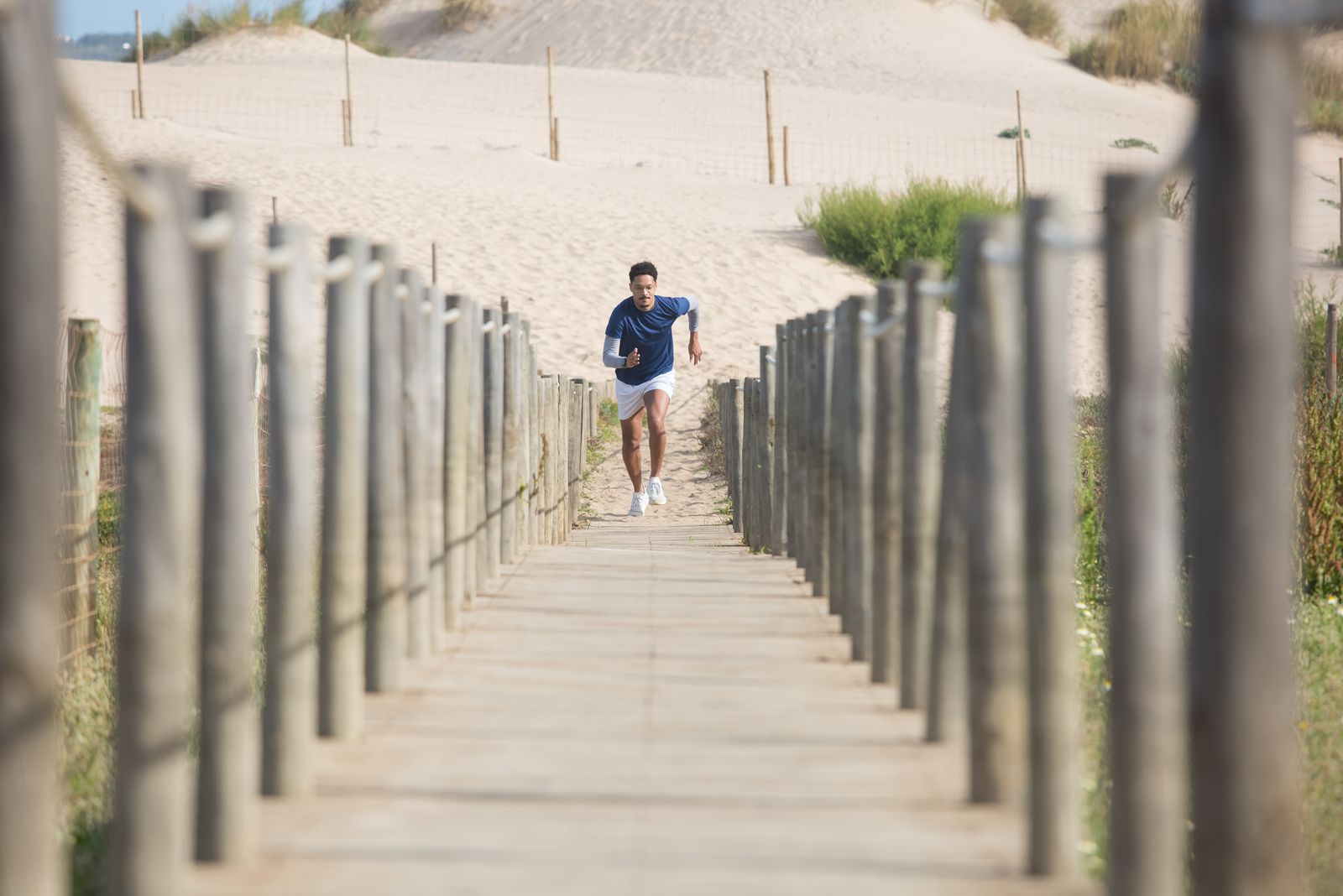 A man running on a boardwalk at the beach for cardio exercise