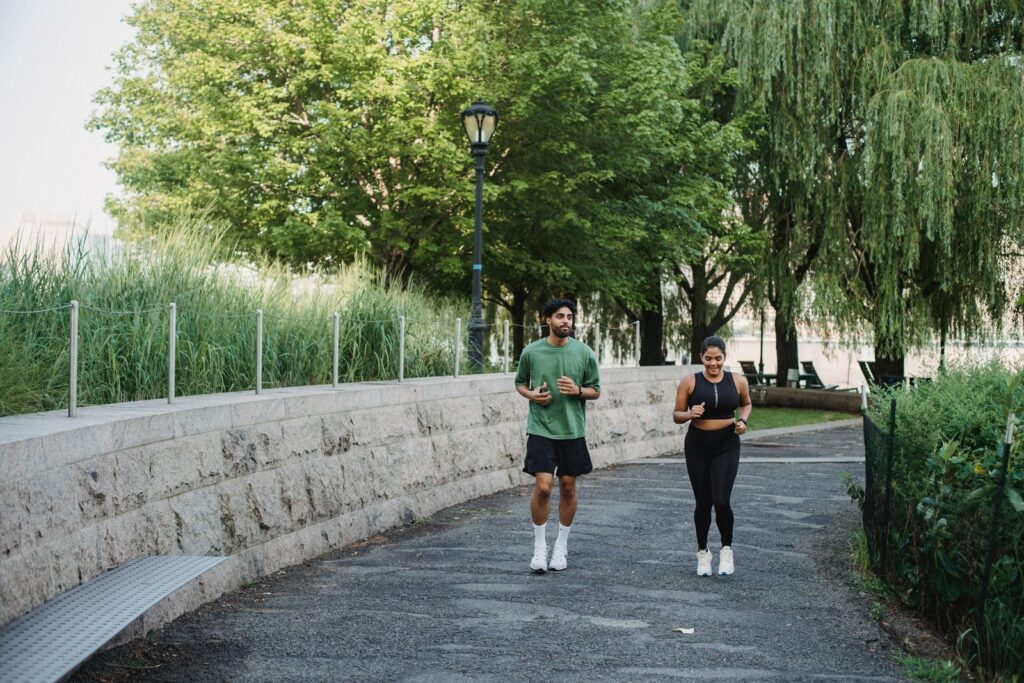 A man and woman jogging together at an easy, conversational pace in a park