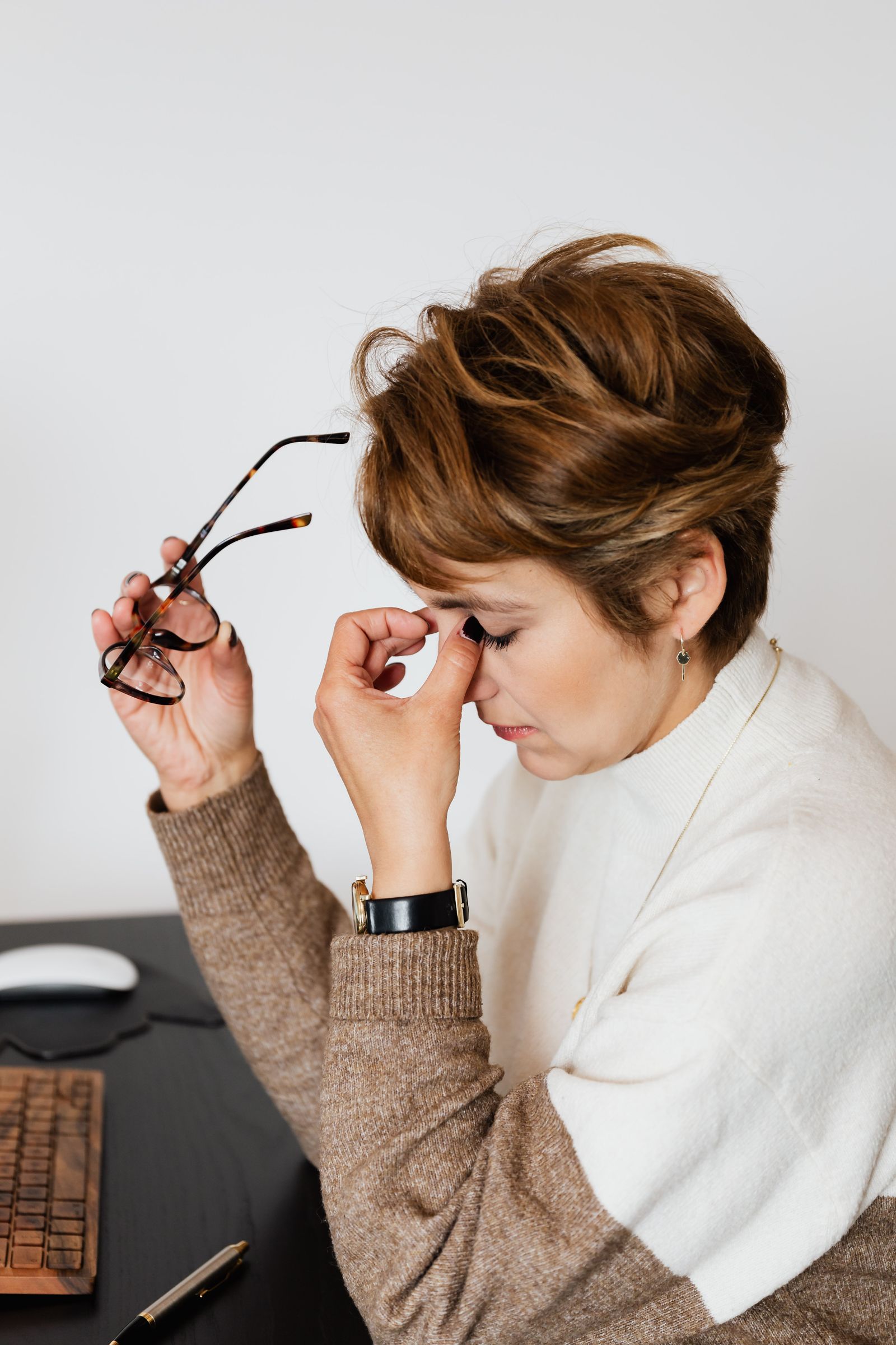 An adult woman feeling stressed and exhausted at her work desk