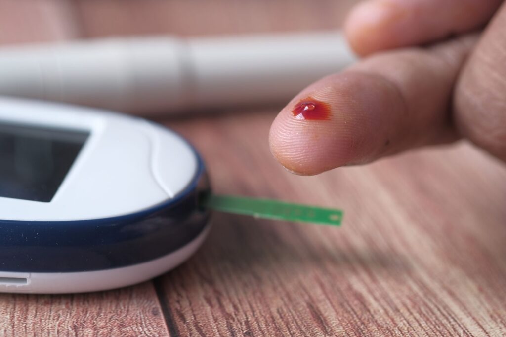 A close-up of a finger prick and blood glucose monitor for diabetes testing