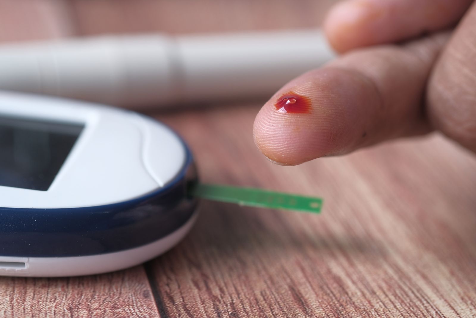 A close-up of a finger prick and blood glucose monitor for diabetes testing