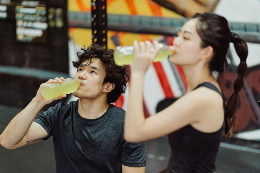 A fit couple hydrating at the gym after an intense workout