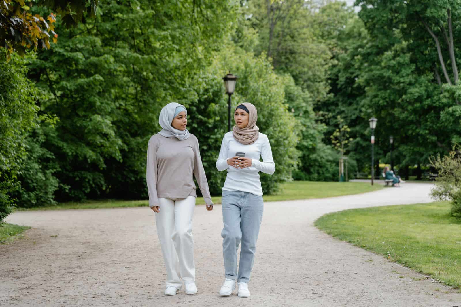 Two friends walking and talking together in a green park