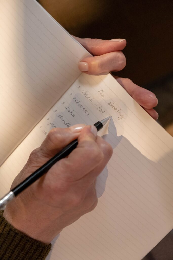 Hands writing a to-do list in a notebook