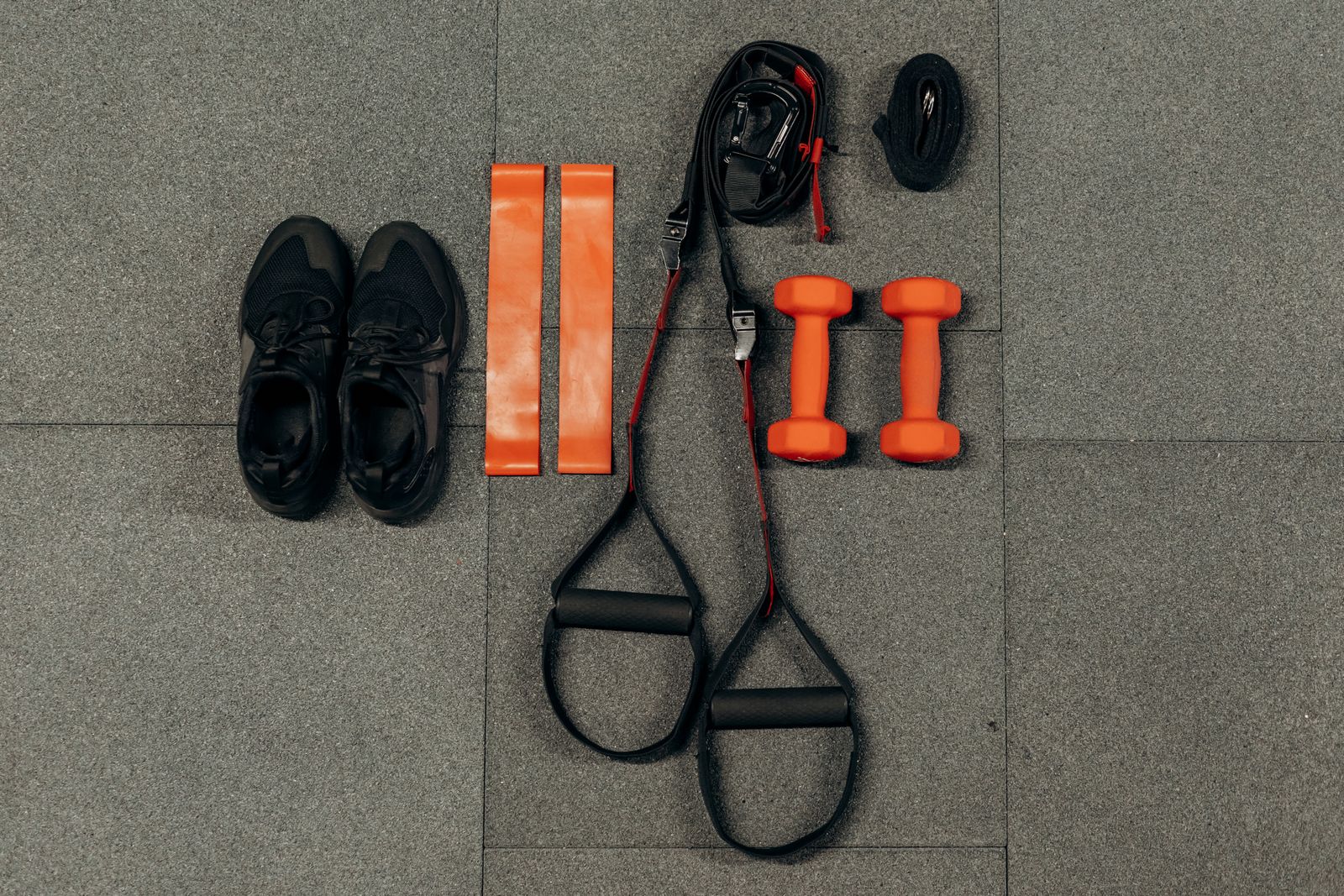 Flat lay of home workout equipment including dumbbells and resistance bands