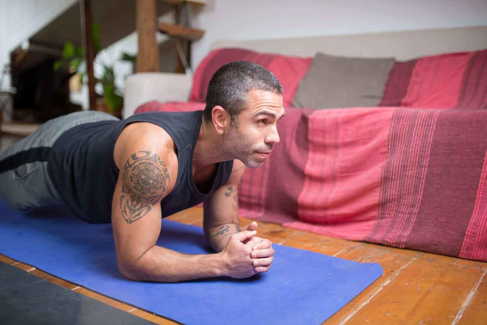 A man holding a plank exercise position on a yoga mat indoors