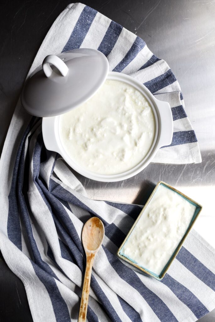 Homemade yogurt in a ceramic pot with a wooden spoon
