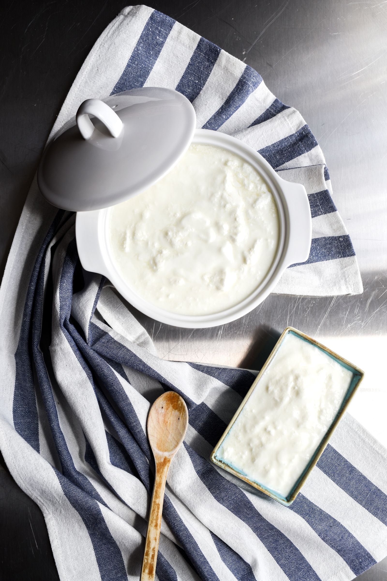 Homemade yogurt in a ceramic pot with a wooden spoon