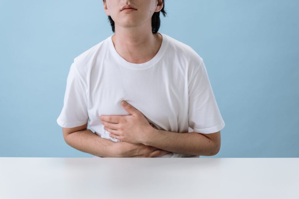 An adult man holding his stomach, indicating pain and discomfort
