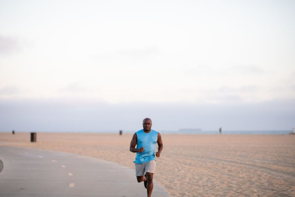 A man jogging on a beach path, building cardiovascular fitness