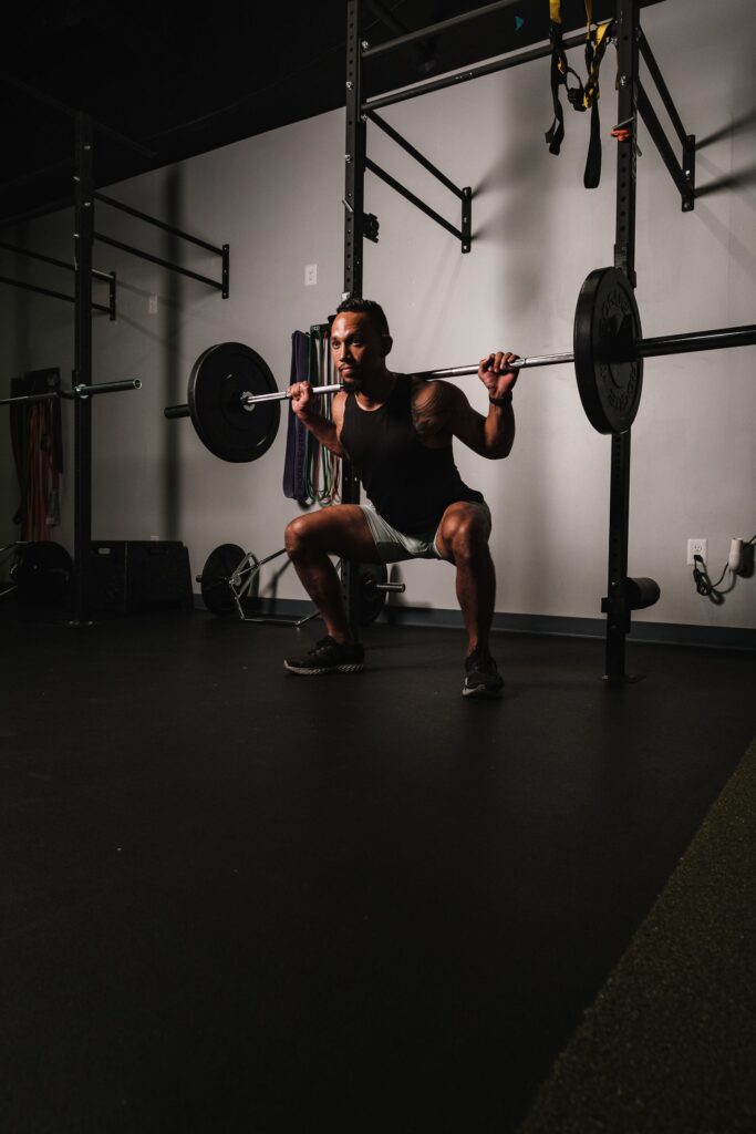 A muscular man performing barbell squats in the gym