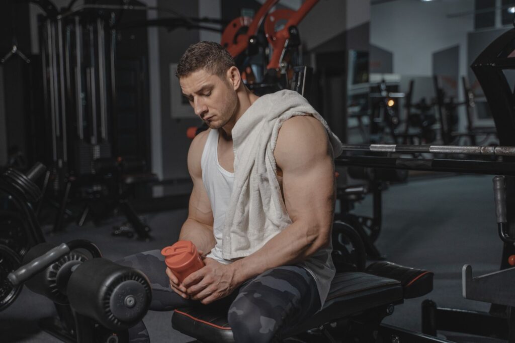 A man holding a protein shaker after a workout at the gym