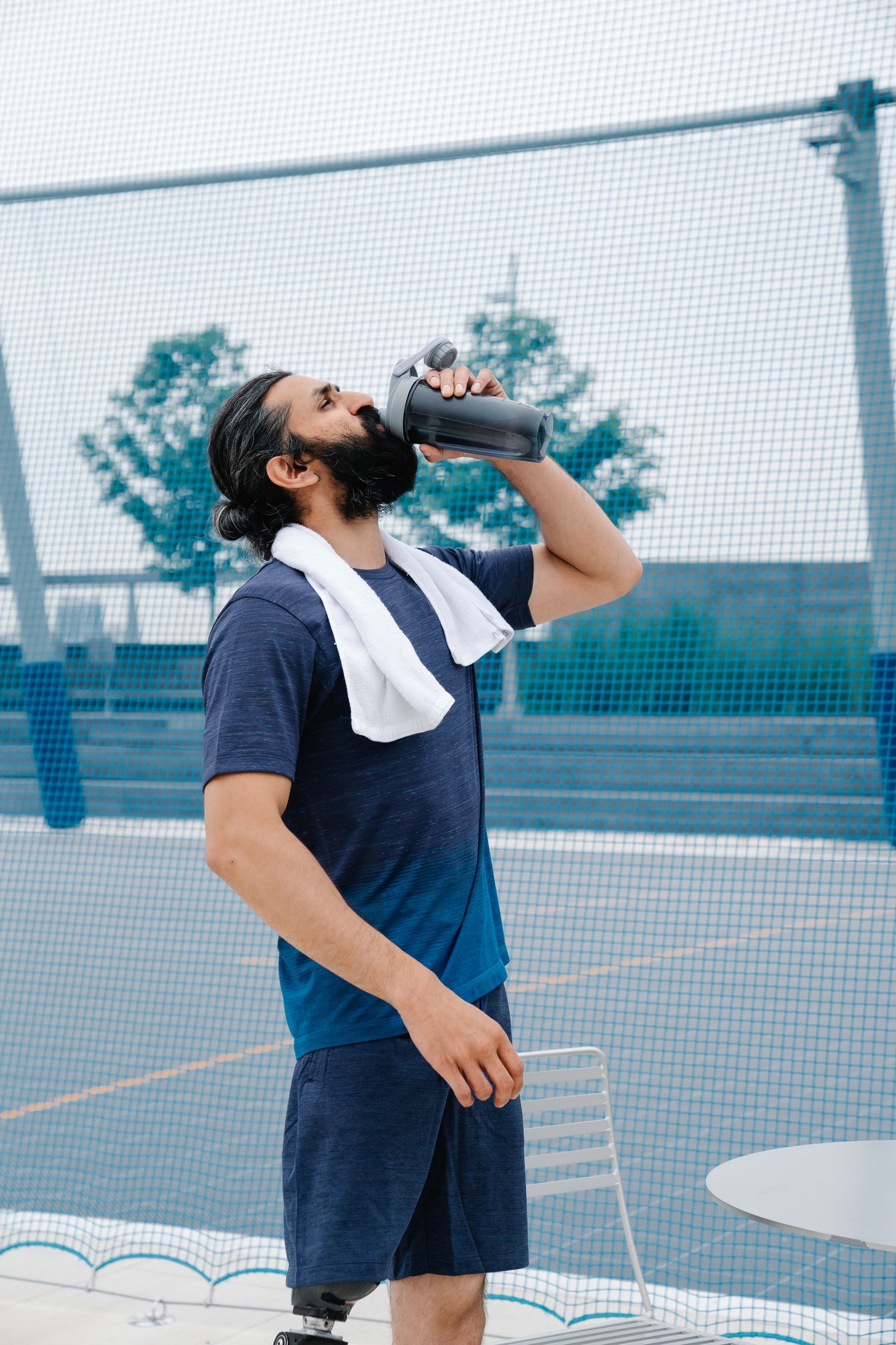 A man in sportswear drinking water outdoors after exercising