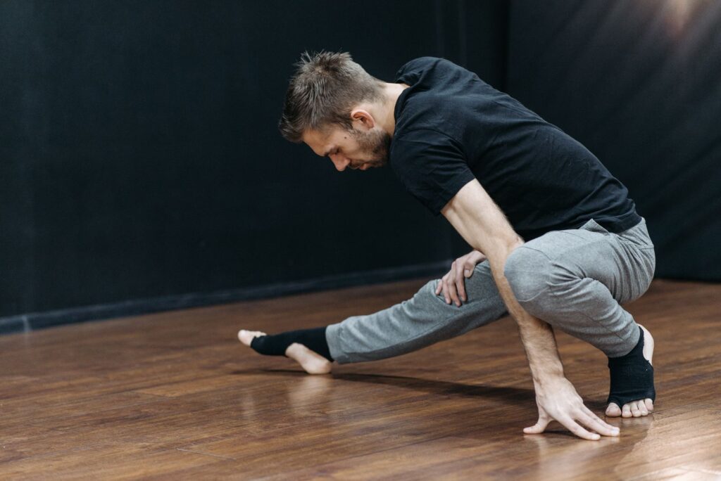 A man stretching in a dance studio, emphasizing flexibility and balance