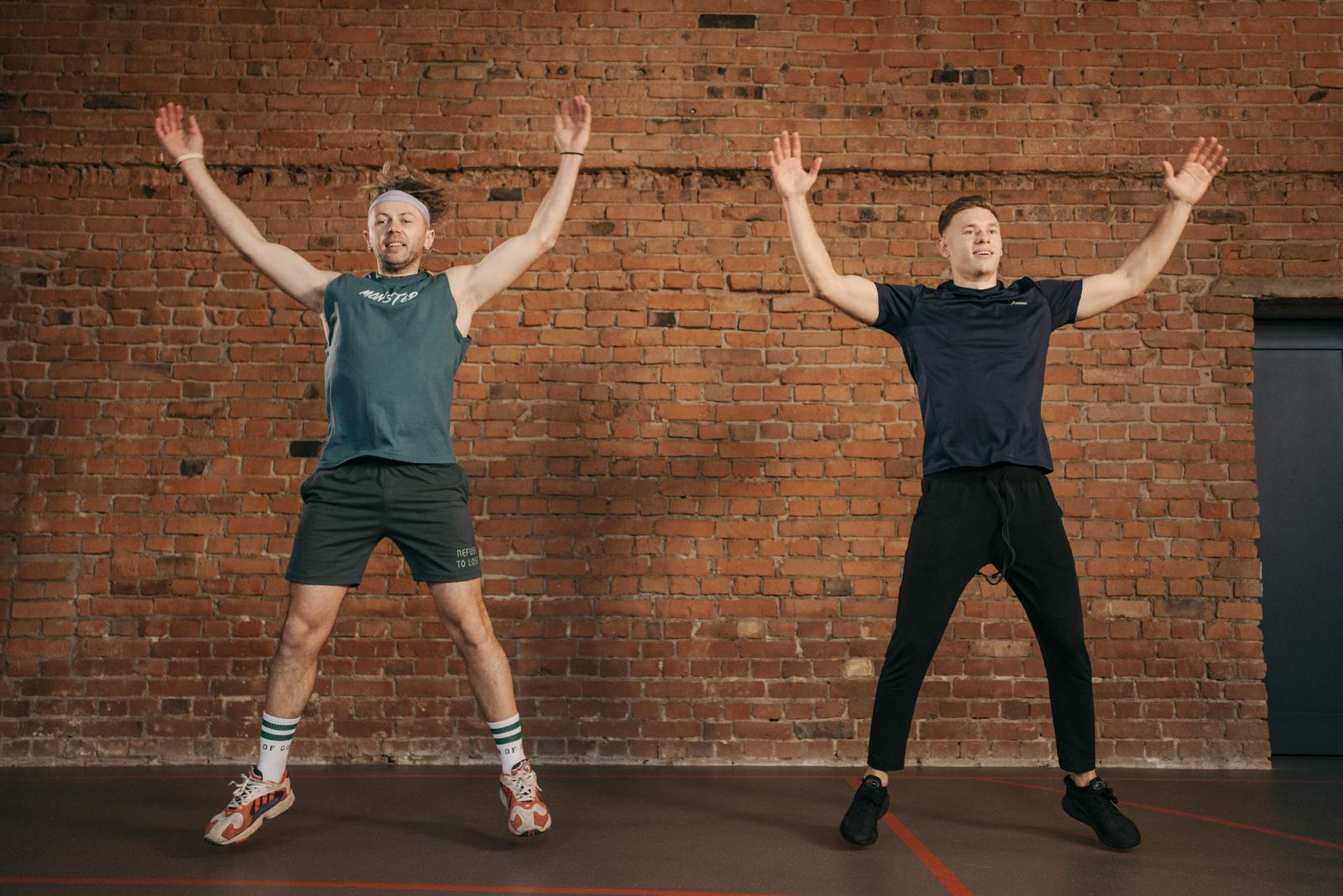 Two men performing jumping jacks as part of a warm-up