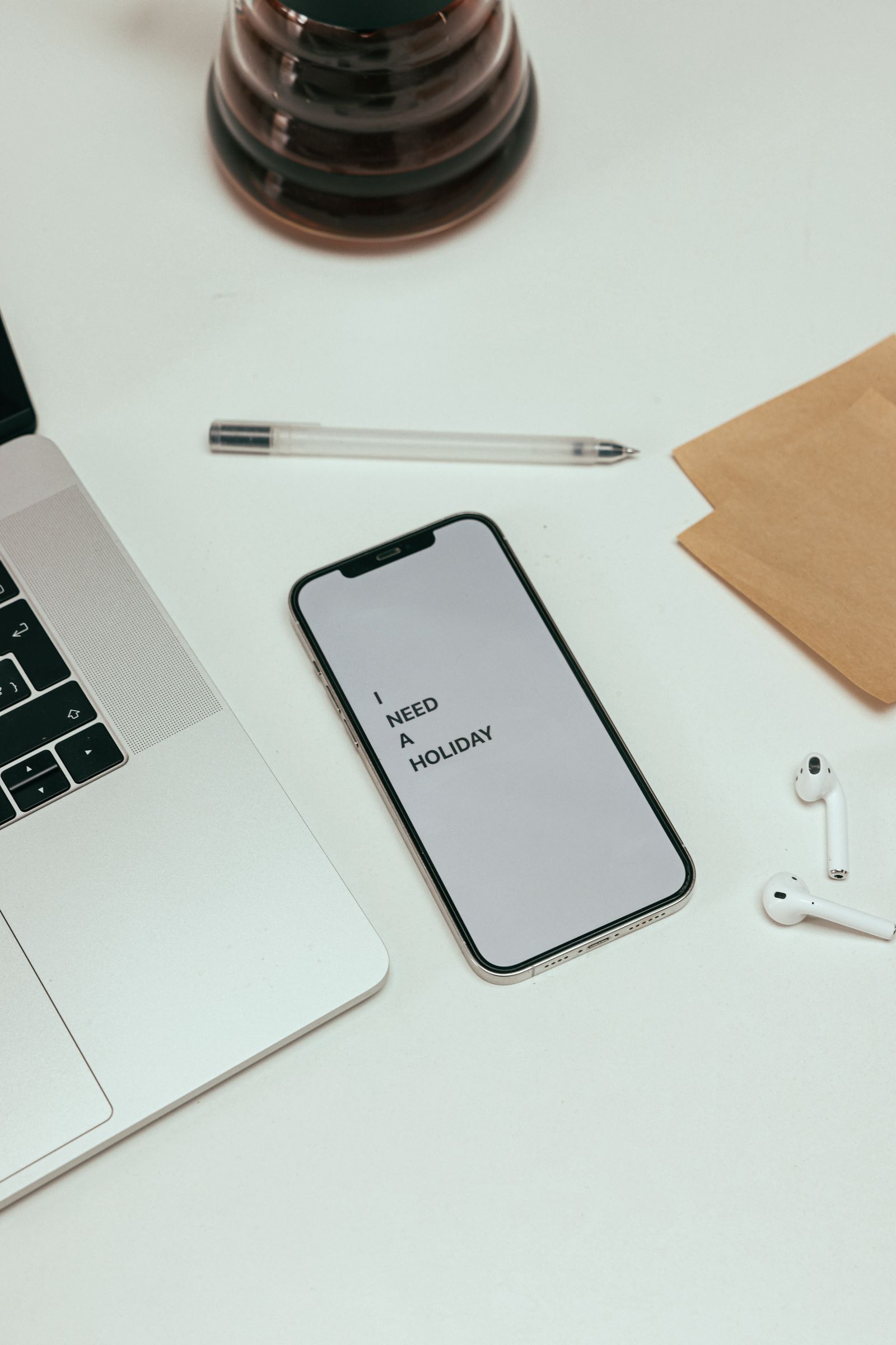 Overhead view of a modern minimalistic workspace with a smartphone, laptop, and earbuds