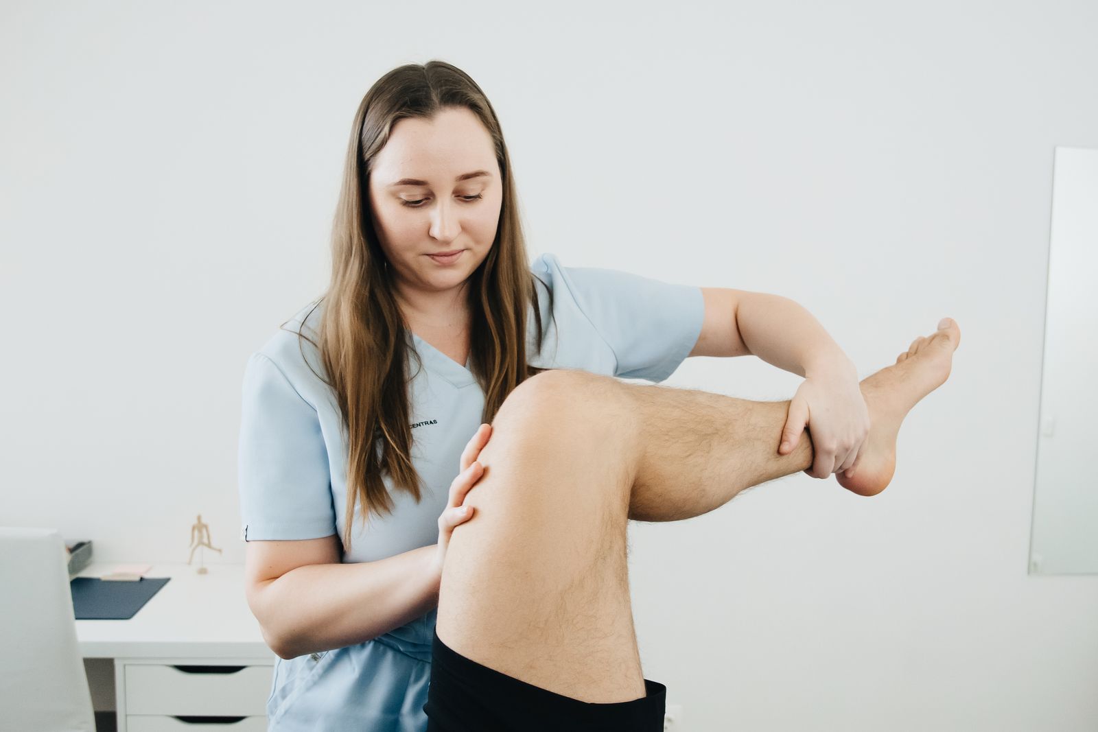 A physiotherapist examining a patient’s leg during a rehabilitation session