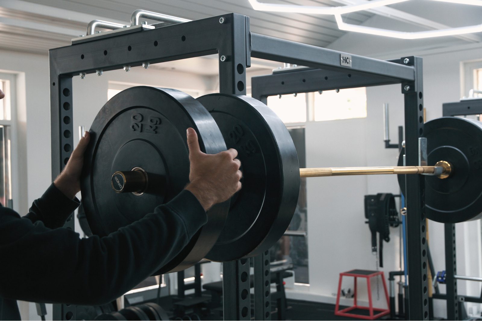 A person adjusting a barbell to add weight for progressive overload