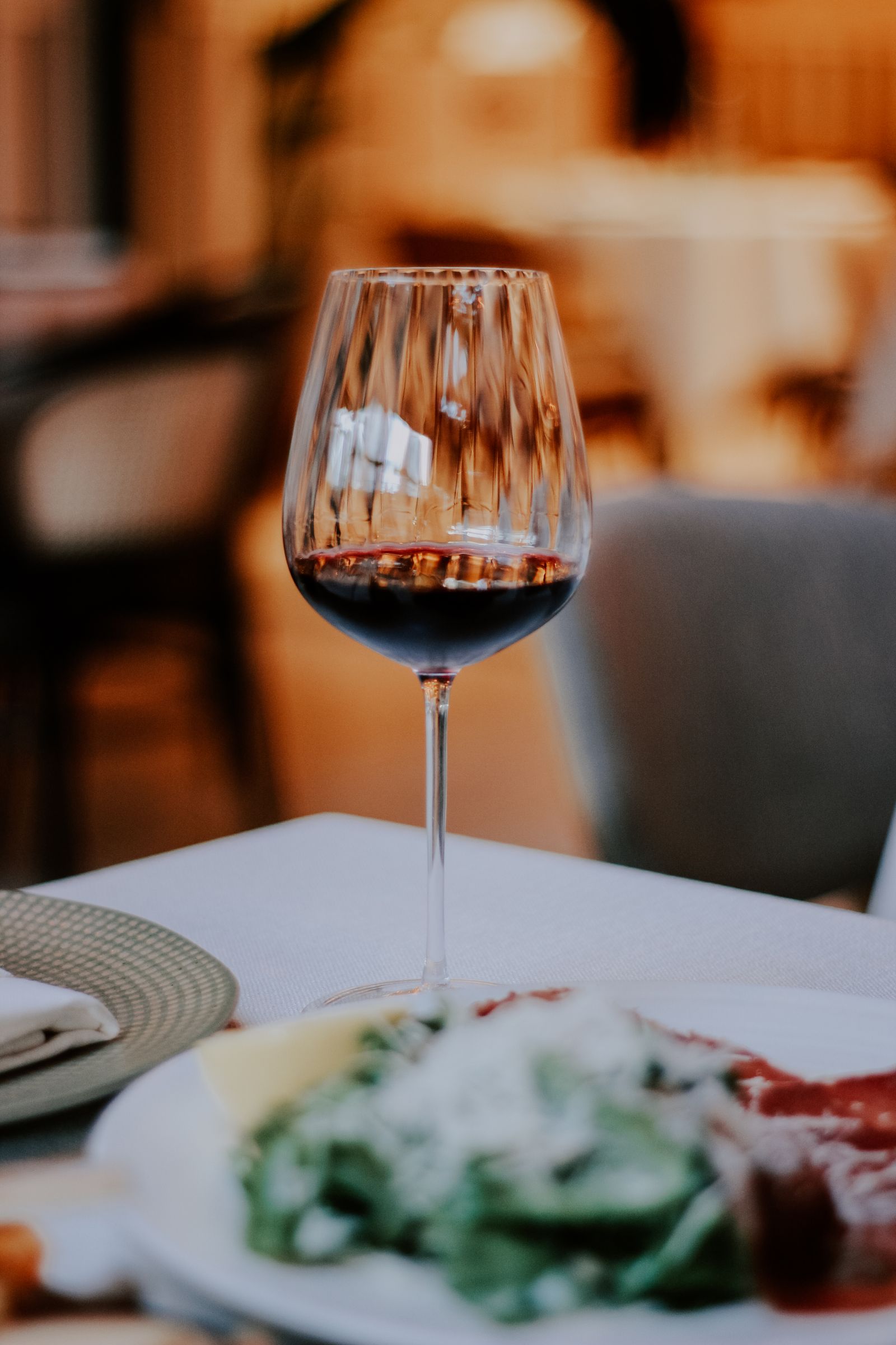A glass of red wine on a table during an evening meal