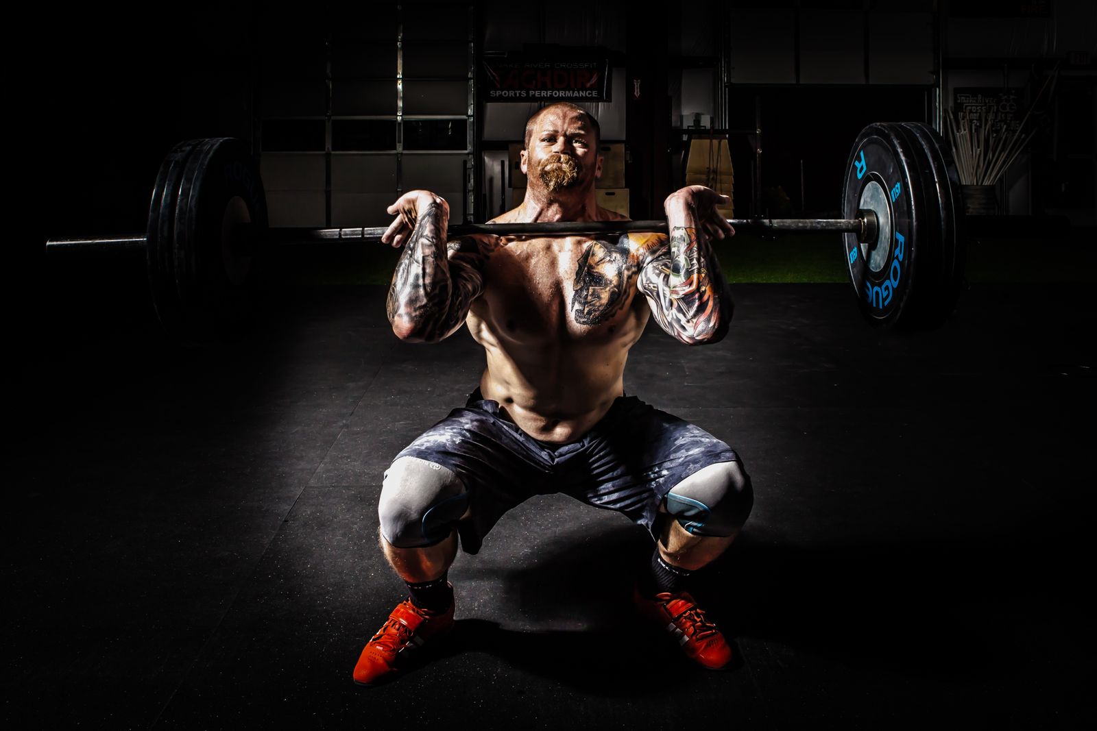 A man performing a heavy barbell squat with visible maximal effort
