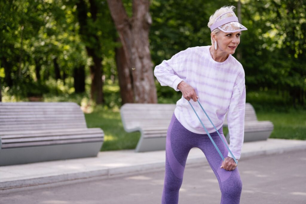 A senior woman performing outdoor exercise with a resistance band in a park