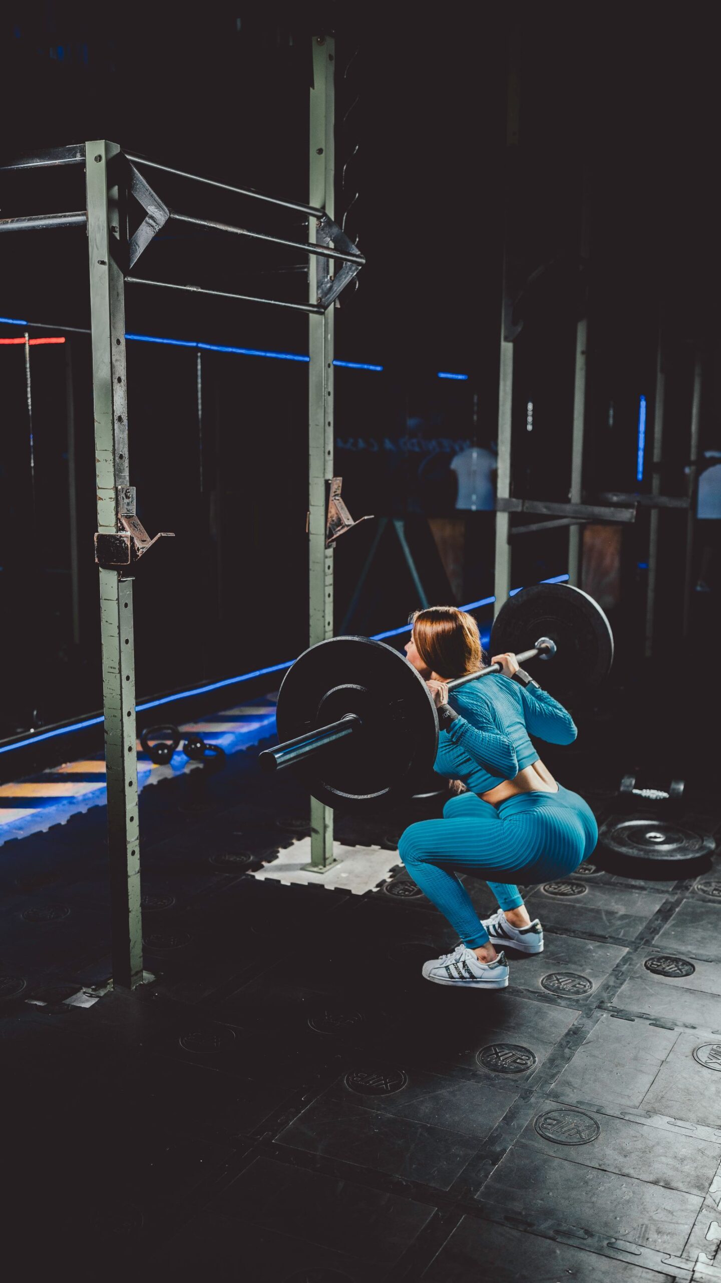 A woman performing a barbell squat with proper form in a gym