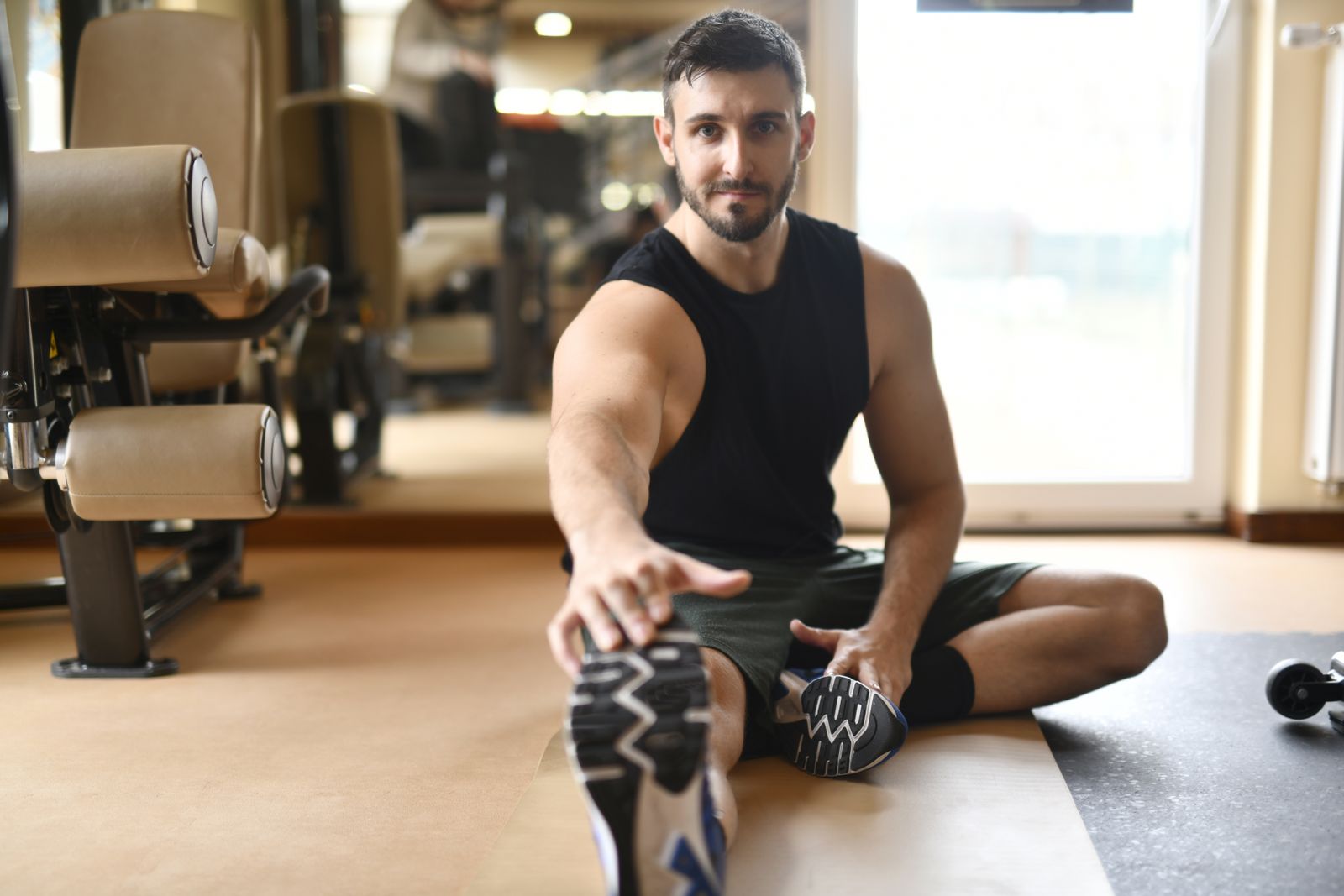 Man stretching on gym floor as part of post-workout recovery