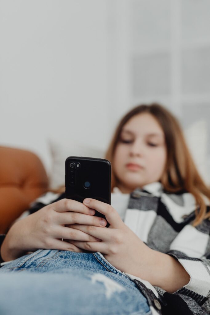 A teenager lying on a couch using a smartphone