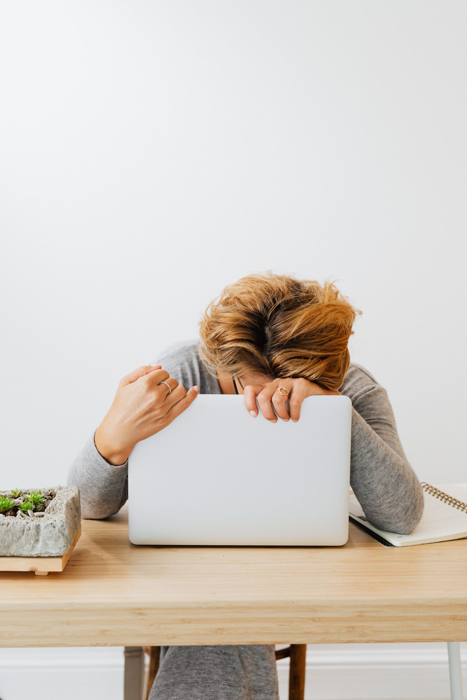 A woman resting her head on a desk showing signs of fatigue, a common symptom of iron deficiency