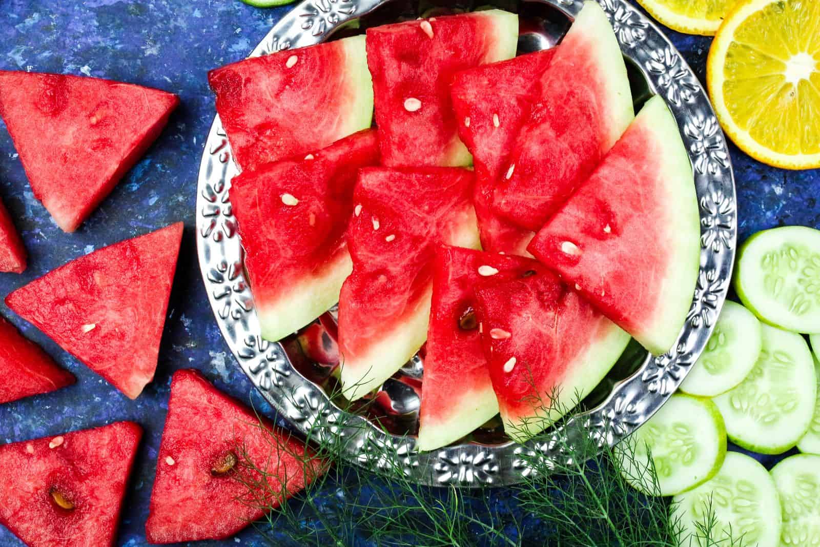 Freshly sliced watermelon, cucumber, and citrus on a plate