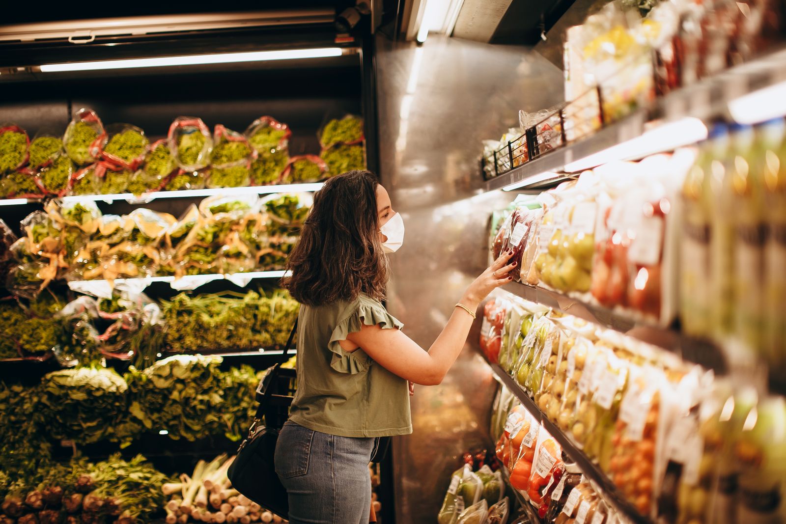 A woman choosing fresh produce in a supermarket aisle