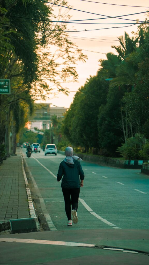 A woman jogs down a quiet street during sunrise