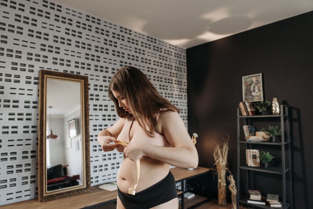 A young woman measuring her waist in a modern room with a mirror