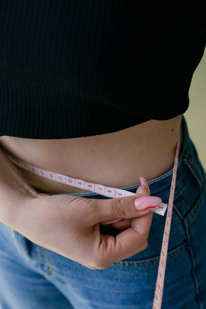 A woman measuring her waist with a tape measure
