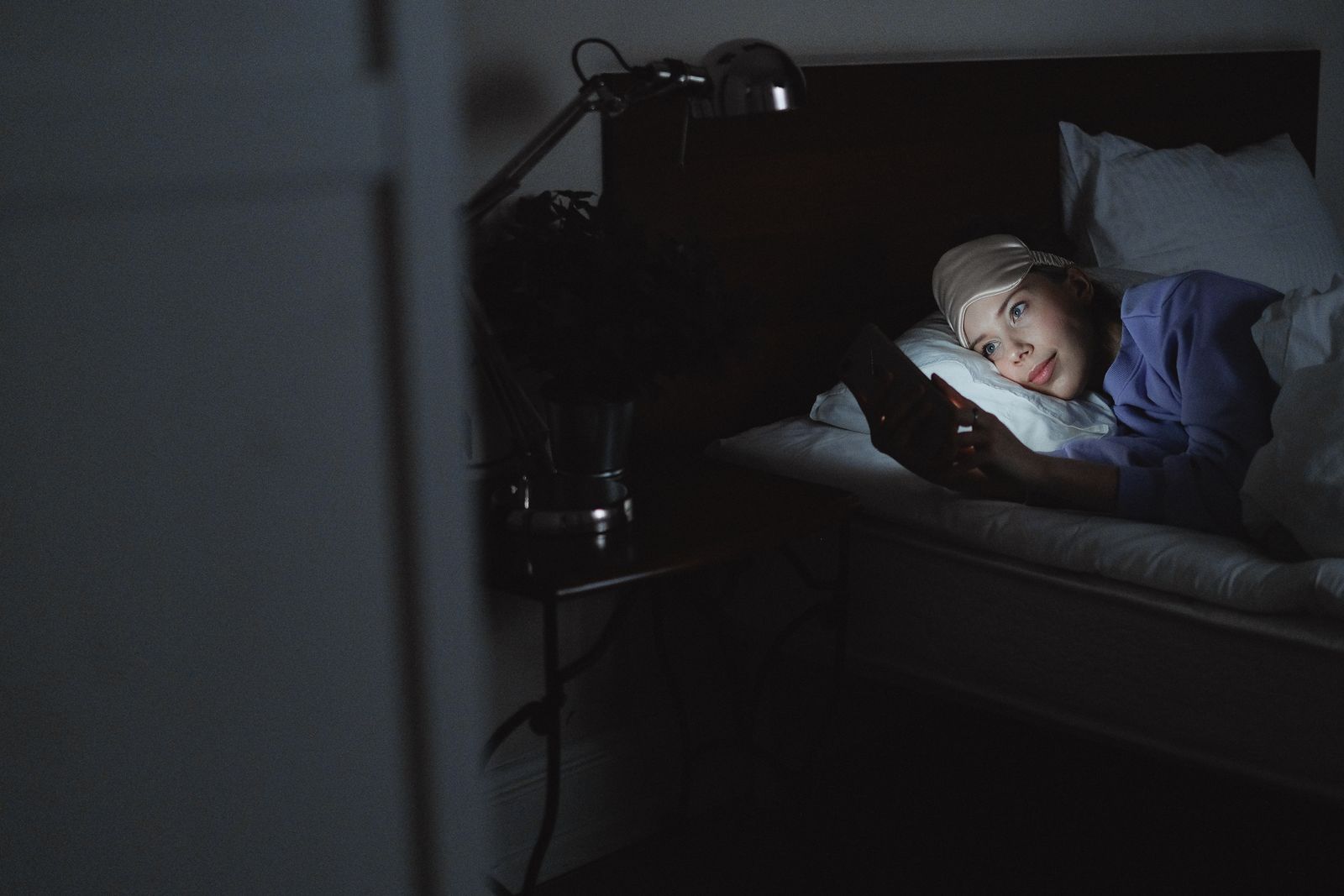A woman using a smartphone in bed at night