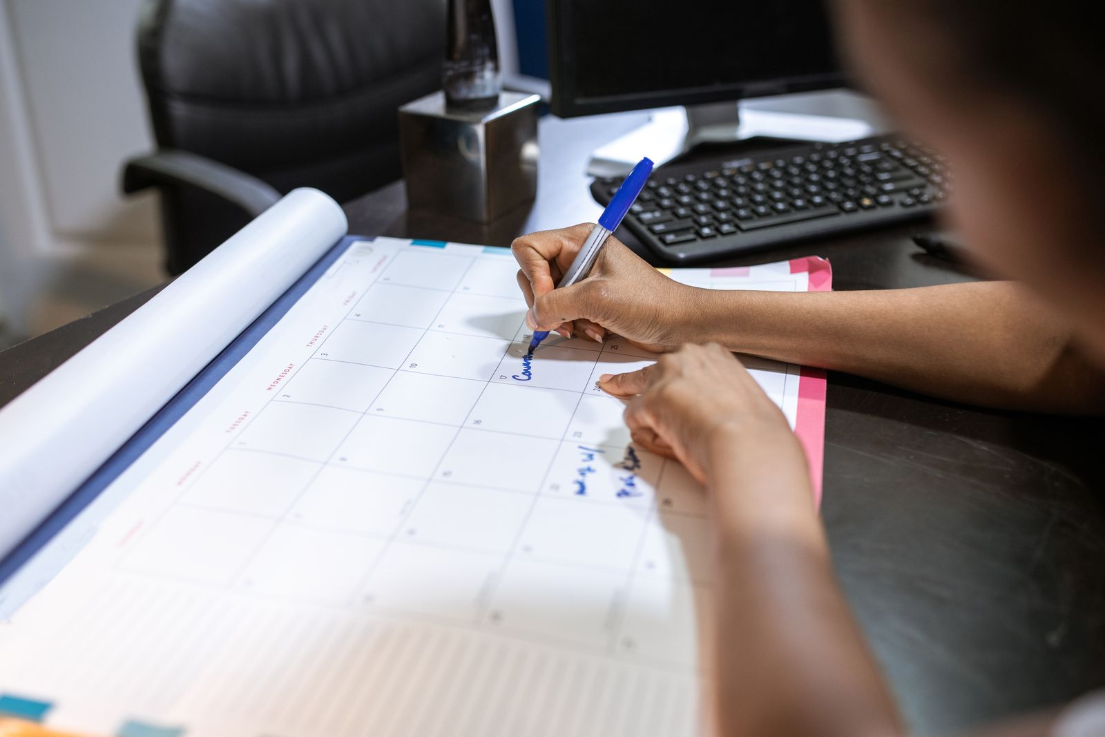 A woman planning her schedule on a desk calendar in an office setting