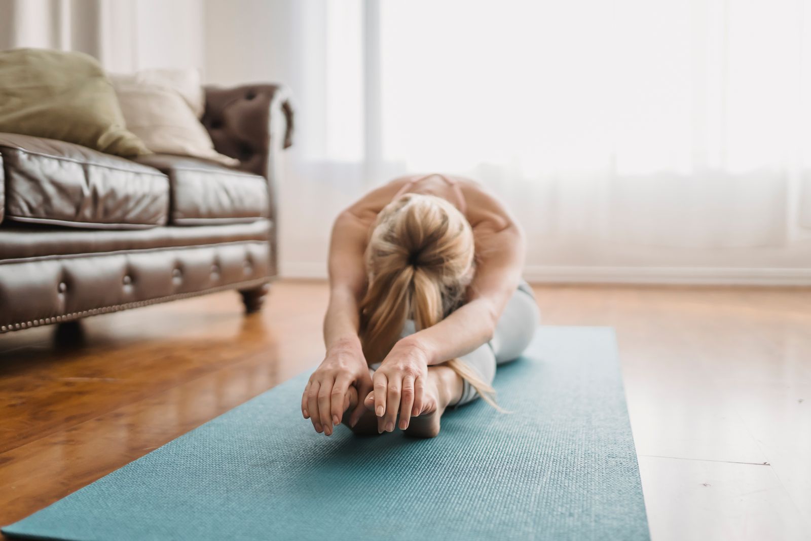 Woman doing a gentle seated forward bend yoga stretch for active recovery
