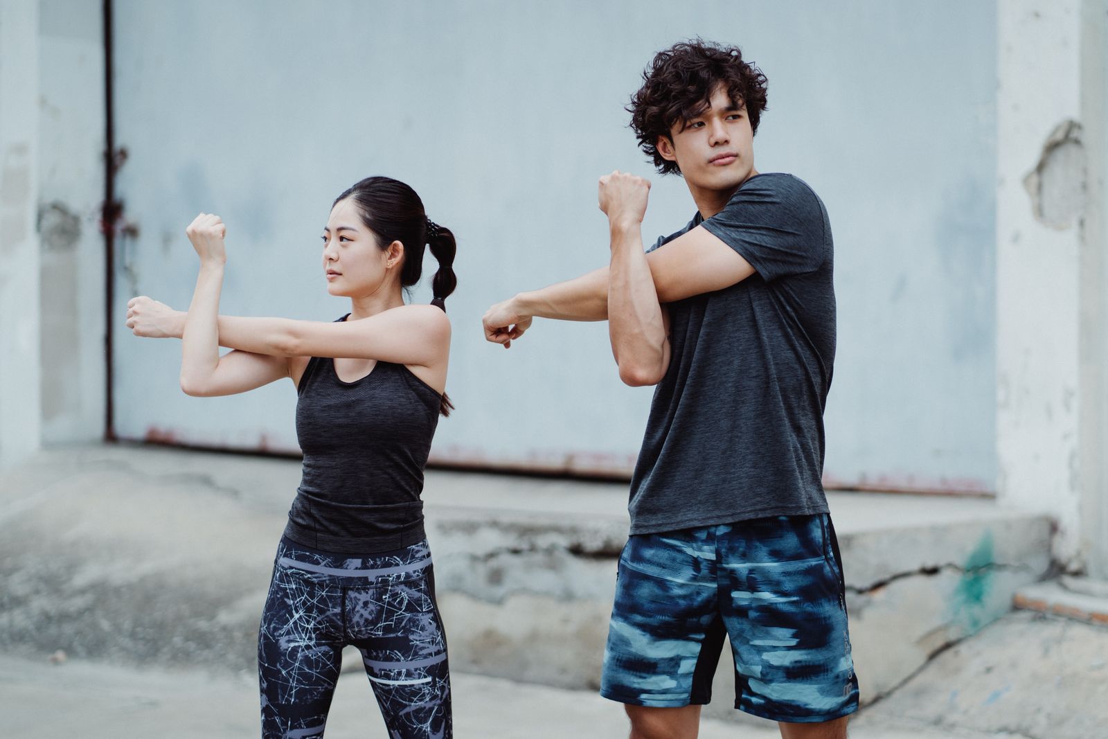 A young couple in activewear stretching outdoors